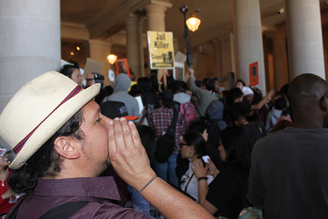 A protester adds his shout to the din inside City Hall. Photo by Laura Wenus