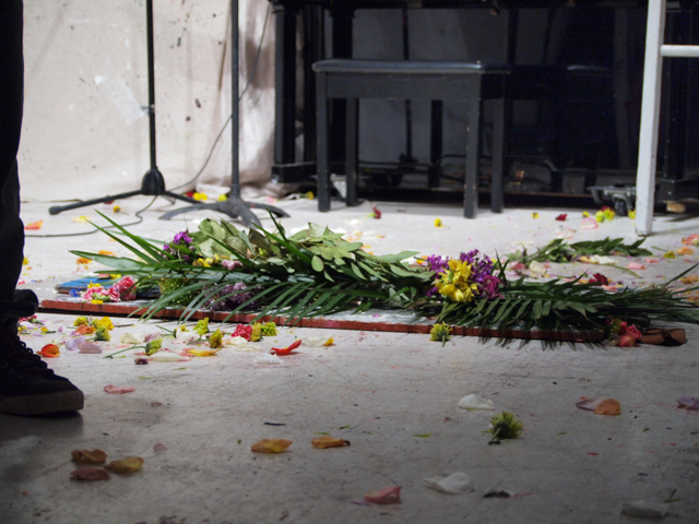 The hole in the art house floor, covered by a plank and flowers at the end of the event. One guest did accidentally fall in the hole during the event, just after 7 p.m., bumping her knee. She had been headed to the piano with sheet music. 