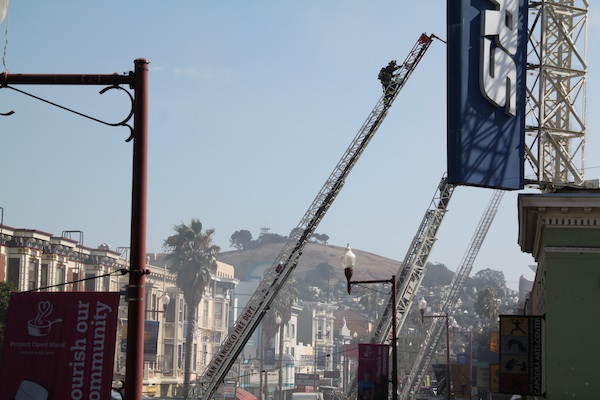 A firefighter climbs a ladder as 5-alarm fire on Mission Street wares down. Photo by Daniel Hirsch.
